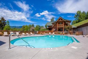 a swimming pool in front of a log cabin at Misty Mountain Hideaway, 3 Bedrooms, Sleeps 10, Pool Access, WiFi in Pigeon Forge
