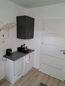 eine Küche mit weißen Schränken und einem schwarzen Schrank in der Unterkunft Apartamenty Via Mare in Ustka