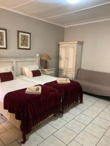 a bedroom with two beds and a couch at Hotel Pension Casa Africana in Windhoek