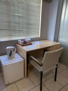 a desk and a chair in a room with a window at Hotel Pension Casa Africana in Windhoek