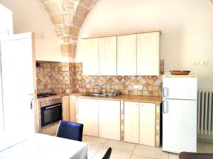 uma cozinha com armários de madeira e um frigorífico branco em Maison de Richard em Ostuni
