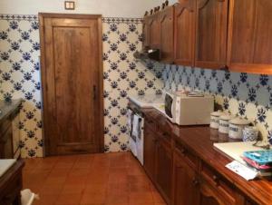 uma cozinha com papel de parede azul e branco e um micro-ondas em Casa Mata da Ribeira em Barcelos