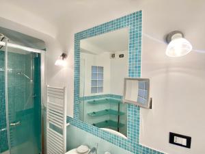 y baño de azulejos azules con ducha y espejo. en CasaViva - Comfy Central Bilo in Genova, en Génova