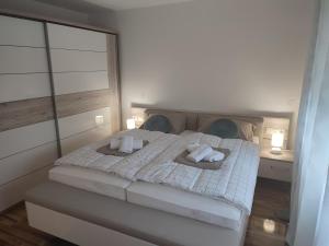 Un dormitorio con una cama blanca con toallas. en Apartmani CARPE DIEM en Draškovec