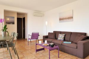 a living room with a couch and a table and chairs at Résidence MARINA SERENA in Porto-Vecchio