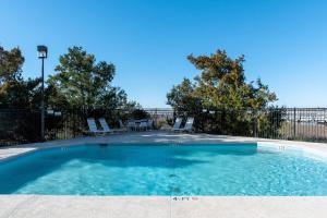 uma piscina com cadeiras, uma mesa e árvores em Bay Creek Villa - 304 em Edisto Island