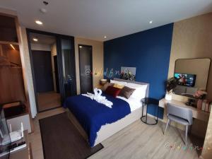 1 dormitorio con 1 cama grande y pared azul en Edge Central Pattaya by JJJ en Pattaya Central