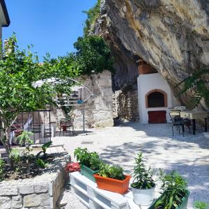 ein Steingebäude mit einem Tisch, Stühlen und Pflanzen in der Unterkunft Vintage stone house ELDO in Podaspilje, Omiš in Omiš