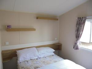 a small bedroom with a bed and a window at Kingfisher : Vacation III:- 6 Berth, Close to site entrance in Ingoldmells