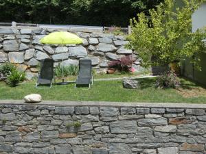 two chairs and an umbrella next to a stone wall at Haus Harmonie in Millstatt