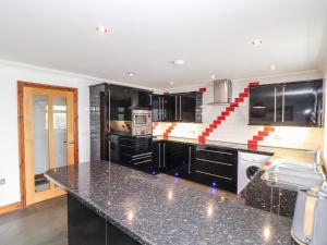 a kitchen with black cabinets and a black counter top at Took Some Doing in Bodmin