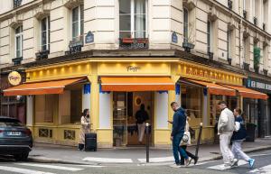 um grupo de pessoas atravessando uma rua em frente a uma loja em Le Garage em Paris