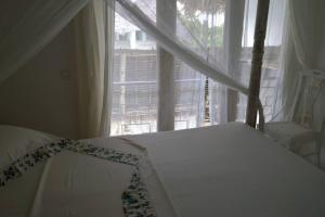 sypialnia z łóżkiem i dużym oknem w obiekcie Swordfish Villas Samaki House (n.4) w mieście Malindi