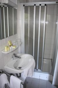 ein weißes Bad mit einem Waschbecken und einer Dusche in der Unterkunft Hotel Haus Hubertus in Schneverdingen