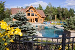 ein Haus mit einem Pool vor einem Zaun in der Unterkunft Fiddler Lake Resort Chalet 96 Elk in Mille-Isles