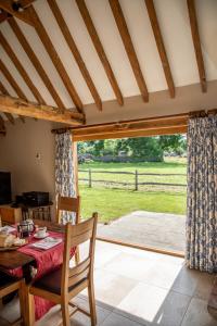 uma sala de jantar com uma mesa e vista para um campo em The Cowshed em Hooe