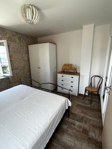 1 dormitorio con 1 cama, armario y silla en Stone house Kurtić stara Podgora, en Podgora