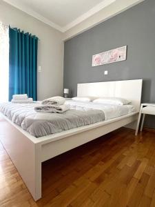 ein großes weißes Bett in einem Schlafzimmer mit blauen Vorhängen in der Unterkunft Mario's comfortable local apartment, next to metro station, close to Acropolis in Athen