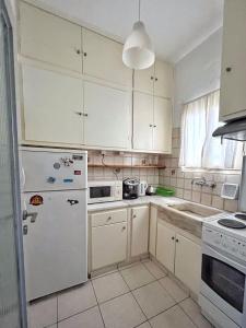 een keuken met witte kasten en een witte koelkast bij Mario's comfortable local apartment, next to metro station, close to Acropolis in Athene
