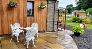 a patio with white chairs and a table and a building at Solheimir at Strathmore Golf Course in Blairgowrie