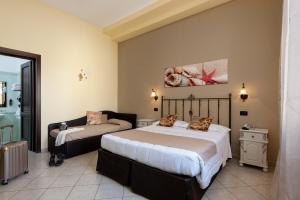 a bedroom with two beds and a couch in it at Il Giardino del Sol in San Vito lo Capo