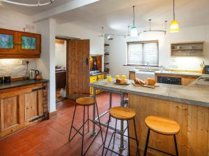 a kitchen with wooden cabinets and bar stools at The Cottage in Stockton on Teme