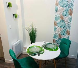 uma mesa branca com cadeiras verdes num quarto em Le Wild Abbeville centre ville baie de Somme em Abbeville