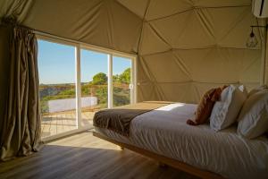 a bedroom with a bed and a large window at Reserva Alecrim EcoSuite & Glamping in Santiago do Cacém