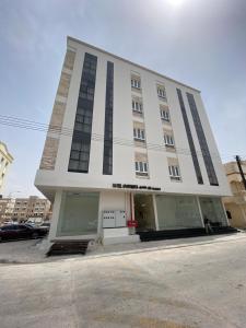 a large white building with windows on a street at Rateel Apartments in Salalah