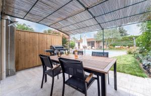 un patio con mesa de madera, sillas y parrilla en Beautiful Home In Villegly With Kitchen, en Villegly