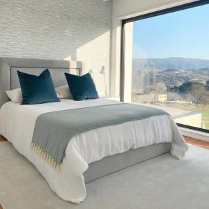 Un dormitorio con una cama grande con una ventana grande. en Moradia - Vila Golfe Amarante, en Amarante