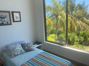 Un dormitorio con una ventana con una cama y una palmera en Nuestra Casa, en Tubará