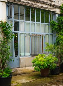 un antiguo edificio con una puerta azul y algunas plantas en Le Garage en París