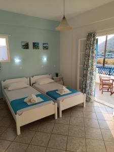 a bedroom with two beds and a balcony at ΑΥΡΑ Ενοικιαζόμενα Δωμάτια - AVRA Rooms To Let in Galissas