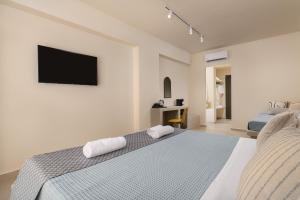 a bedroom with a bed with a television on the wall at Olive Garden Hotel in Lardos