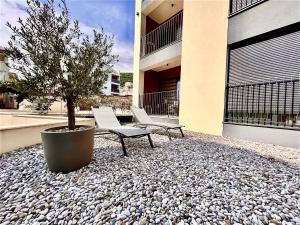 two chairs and a tree in front of a building at Fides Stylish Apartments Tivat with Pool in Tivat
