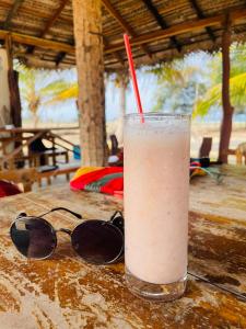 una bebida con una paja roja sentada en una mesa con gafas de sol en Ganesh Gate, en Pottuvil