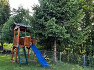 a playground with a blue slide and a tree at House Mirjana in Smoljanac