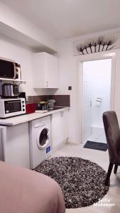 uma cozinha branca com um micro-ondas e uma máquina de lavar roupa em Studio Flat, close to o2 Arena and City Airport em Woolwich