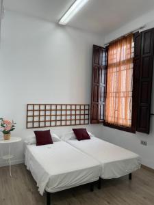 1 dormitorio con 2 camas y ventana en The Cathedral Hostel, en Murcia