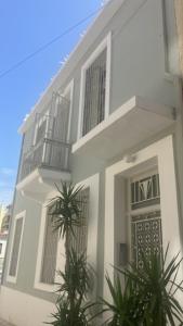 a white house with a balcony and plants in front of it at Jade in Athens