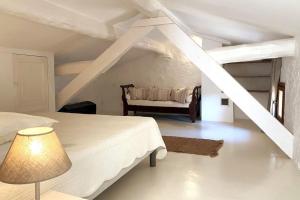 a white bedroom with a bed and a chair at Campagne du XVII au luxe simple in Lorgues