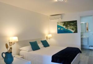 a white bedroom with a large bed with blue pillows at Albergo"Villa Biscotti" in Peschici