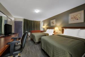 a hotel room with two beds and a desk with a chair at Knights Inn Burlington in Burlington