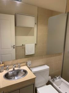 a bathroom with a sink and a toilet and a mirror at Amaru - Departamento céntrico con cochera in Corrientes +24 photos