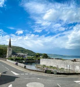 a street with a building and a church and a road at Rose House in Glenarm