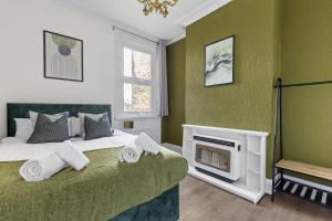 Dormitorio verde con cama y chimenea en Parea Living - Hackney, 4-Bedroom Victorian House w Big Garden, en Londres