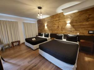 Habitación de hotel con 2 camas y pared de madera. en Bellavista express en Santiago