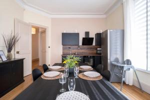 a dining room with a table and chairs and a kitchen at Luxe Poincare in Nancy