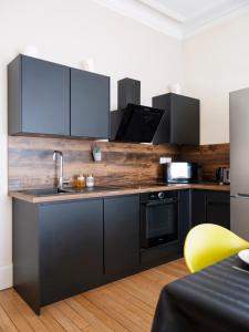 a kitchen with black cabinets and a yellow chair at Luxe Poincare in Nancy